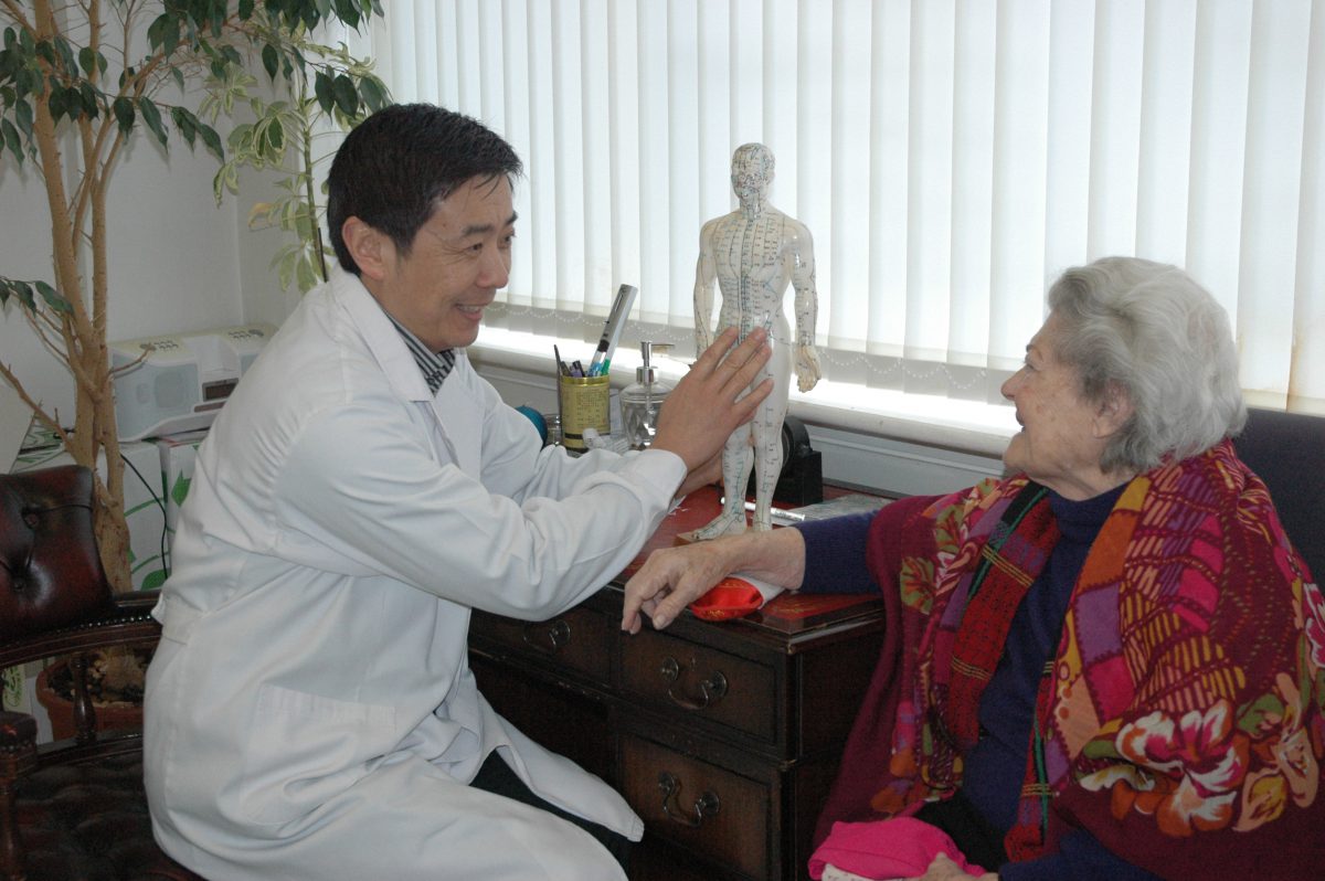 A Herbs Kingdom practitioner explaining acupuncture points to a patient at the Hove clinic